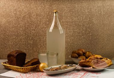 Ukrayna ulusal içecek ve atıştırmalık. Eski tahta masadaki büyük şişe ve bir bardak kaçak içki. Rus votka ve aperatif.