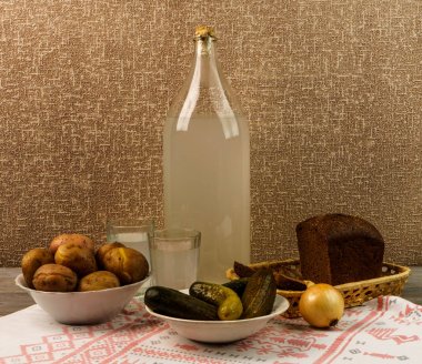 Ukrayna ulusal içecek ve atıştırmalık. Eski tahta masadaki büyük şişe ve bir bardak kaçak içki. Rus votka ve aperatif.