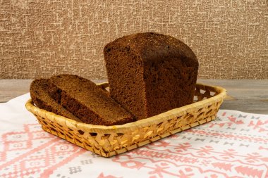 Bir havlu üzerinde bir sepet ayakta çavdar ekmeği dilimlenmiş. Ahşap rustik tablo dilimleri ile taze çavdar ekmek.