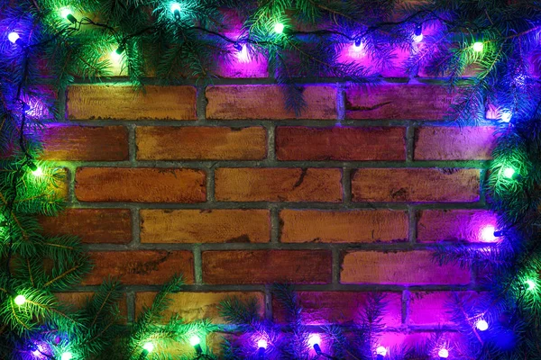 Grinalda e guirlandas de lâmpadas coloridas. Fundo de Natal com luzes e espaço livre de texto. Luzes de Natal na fronteira. Luzes de Natal coloridas brilhantes em um fundo de parede de tijolo. Ano Novo . — Fotografia de Stock