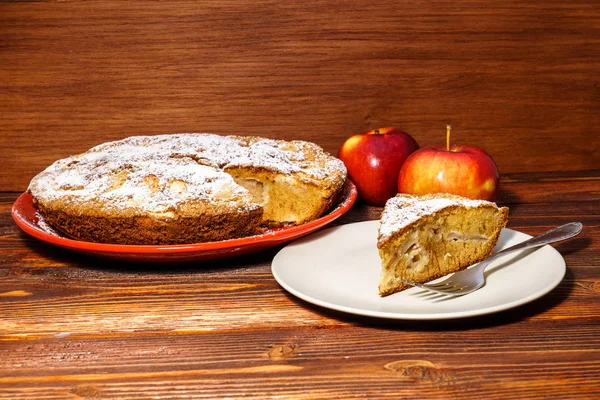 Manzanas frescas y un trozo de tarta de manzana espolvoreada con su polvo — Foto de Stock