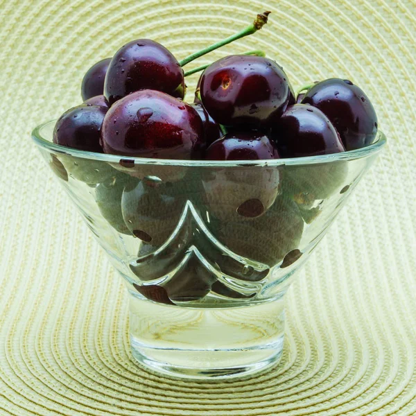Стеклянная ваза со свежими вишнями на белом фоне . — стоковое фото