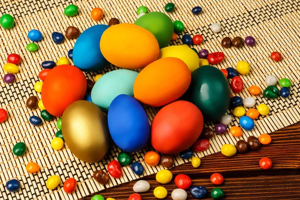 Delicious easter eggs and sweets on a wooden background — Stock Photo, Image