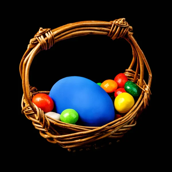 A basket of delicious Easter eggs and sweets isolated on black b — Stock Photo, Image