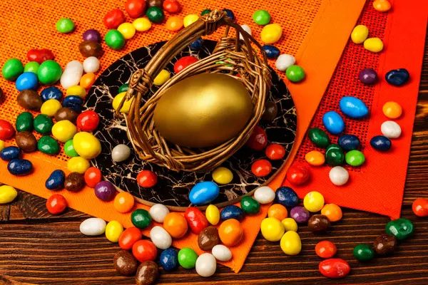 A basket of delicious Easter eggs and sweets on wooden backgroun — Stock Photo, Image