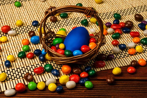 A basket of delicious Easter eggs and sweets on wooden backgroun — Stock Photo, Image