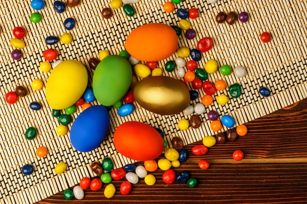 Delicious easter eggs and sweets on a wooden background — Stock Photo, Image