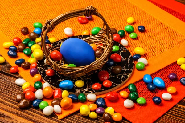 A basket of delicious Easter eggs and sweets on wooden backgroun — Stock Photo, Image