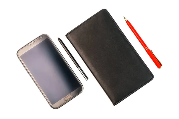 Uno smartphone con penna stilografica e un notebook nero con penna rossa — Foto Stock