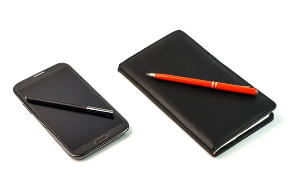 Uno smartphone con penna stilografica e un notebook nero con penna rossa — Foto Stock