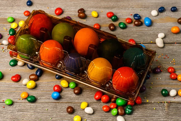 Tray with delicious colored Easter eggs and sweets on wooden bac — Stock Photo, Image
