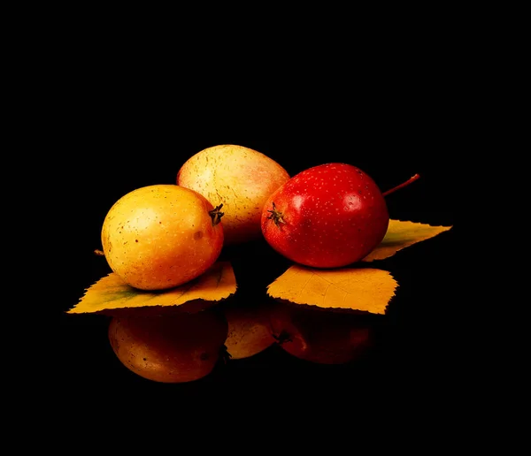 Zralá divoká jablka se žlutými podzimními listy izolované na černém pozadí — Stock fotografie