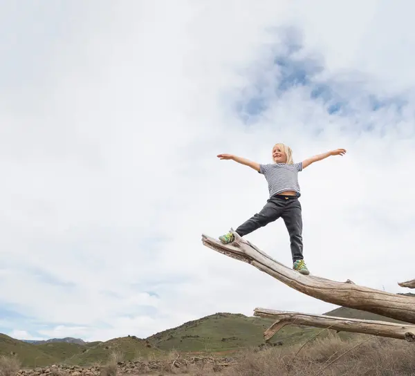 Boy balancing on end of tree trunk — Stock Photo, Image