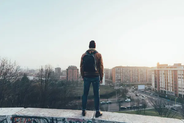 Hipster standing on city wall looking out — Stock Photo, Image
