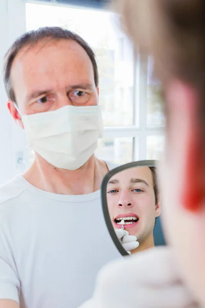 Tannlege som viser pasienten tennene – stockfoto