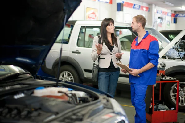 車の修理を議論する車の整備士と顧客 — ストック写真