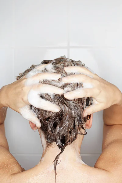 妇女的后方看法洗涤她的头发在阵雨 — 图库照片