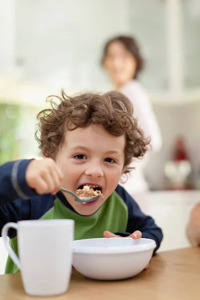 台所で朝食を食べる少年は 前景に焦点を当てます — ストック写真