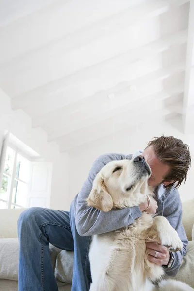 Młody Człowiek Salon Sofa Przytulanie Golden Retriever Pies — Zdjęcie stockowe