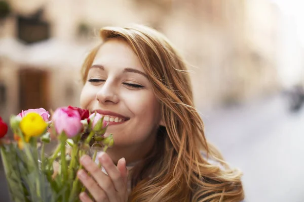 花の束の臭いがする若い女性を笑顔 — ストック写真