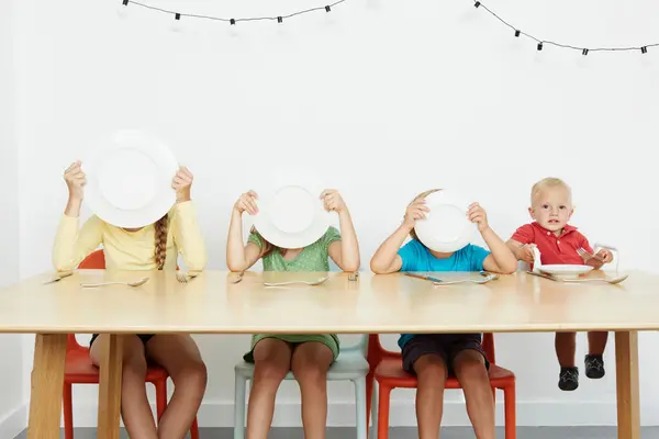 Quatro Crianças Sentadas Mesa Três Faces Cobertas Com Placas — Fotografia de Stock