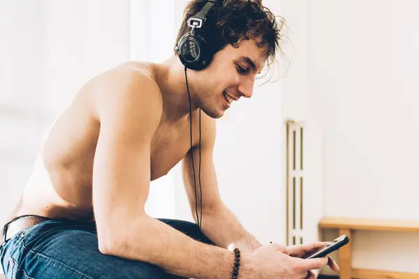 Hombre Pecho Desnudo Con Auriculares Mirando Hacia Abajo Teléfono Inteligente —  Fotos de Stock