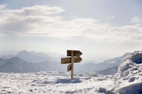 在积雪覆盖的山脉上的木箭标志 — 图库照片