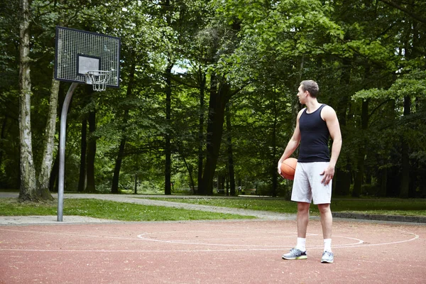 Ung Mandlig Basketballspiller Kigger Skulderen Basketball Hoop - Stock-foto