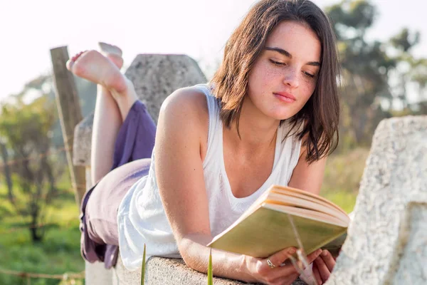 Mädchen liegt im Freien und liest Buch — Stockfoto