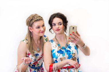 İki genç arkadaş ile mobil akıllı telefon ile fotoğraf çekmek parlak Yazlık elbiseler.