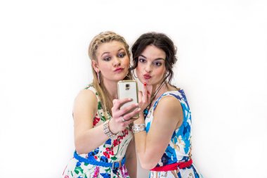 İki genç arkadaş ile mobil akıllı telefon ile fotoğraf çekmek parlak Yazlık elbiseler.