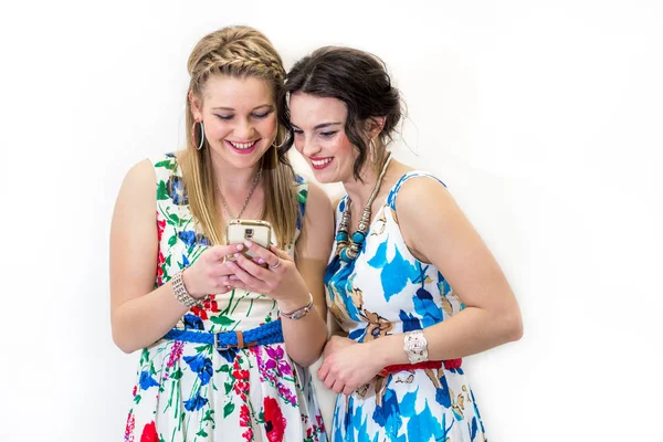 İki genç arkadaş ile seyir mobil akıllı telefon parlak Yazlık elbiseler.