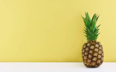 Sarı arka plan üzerinde olgunlaşmış ananas.