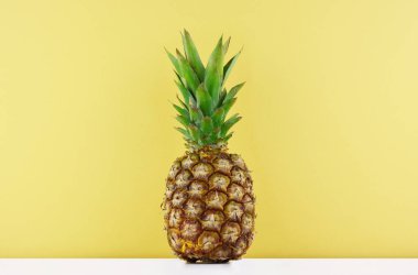 Sarı arka plan üzerinde olgunlaşmış ananas.