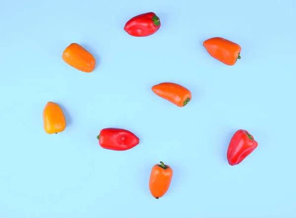 Rood, oranje, gele paprika op blauwe achtergrond. — Stockfoto