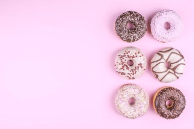 Pembe bir arka plan üzerinde renkli donut.