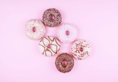 Pembe bir arka plan üzerinde renkli donut.