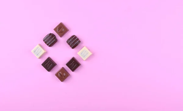 Vários pralines de chocolate no fundo da moda rosa . — Fotografia de Stock