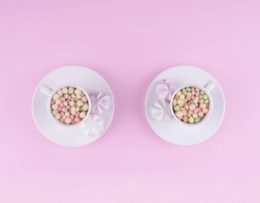 Küçük pastel renkli şeker beyaz bir fincan.