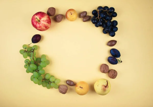 Herbstfrüchte und Nüsse auf gelbem Hintergrund. — Stockfoto