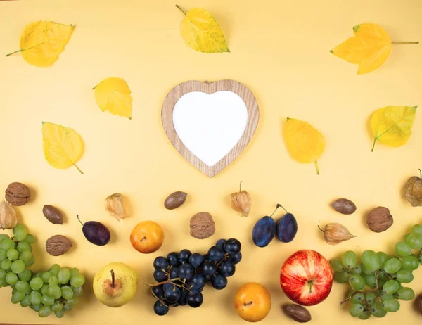 Herbstfrüchte und Nüsse auf gelbem Hintergrund. — Stockfoto