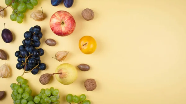 Herbstfrüchte und Nüsse auf gelbem Hintergrund. — Stockfoto