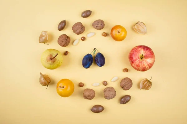 Осенние фрукты и орехи на желтом фоне . — стоковое фото