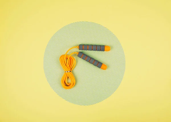 Cuerda de salto naranja o saltar la cuerda sobre fondo amarillo y verde — Foto de Stock