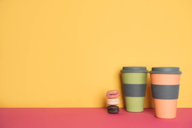 Sarı ve pembe arka plan üzerinde macaron ile kahve fincan