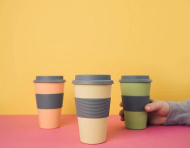 Renkli kağıt arka plan üzerinde kahve bardakları götürün.