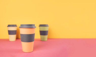 Renkli kağıt arka plan üzerinde kahve bardakları götürün.