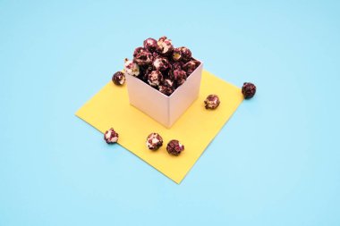 Kağıt bardak mavi ve Sarı zemin üzerine tadında berry ile pembe patlamış mısır.