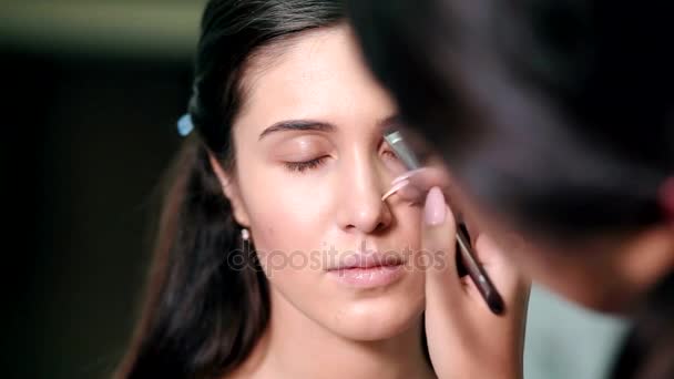 Maquillaje artista haciendo perfecto maquillaje de chica joven — Vídeos de Stock