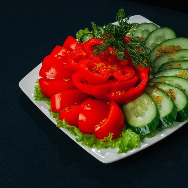 Salade met tomaat paprika en komkommer, voedsel close-up, zwarte achtergrond — Stockfoto
